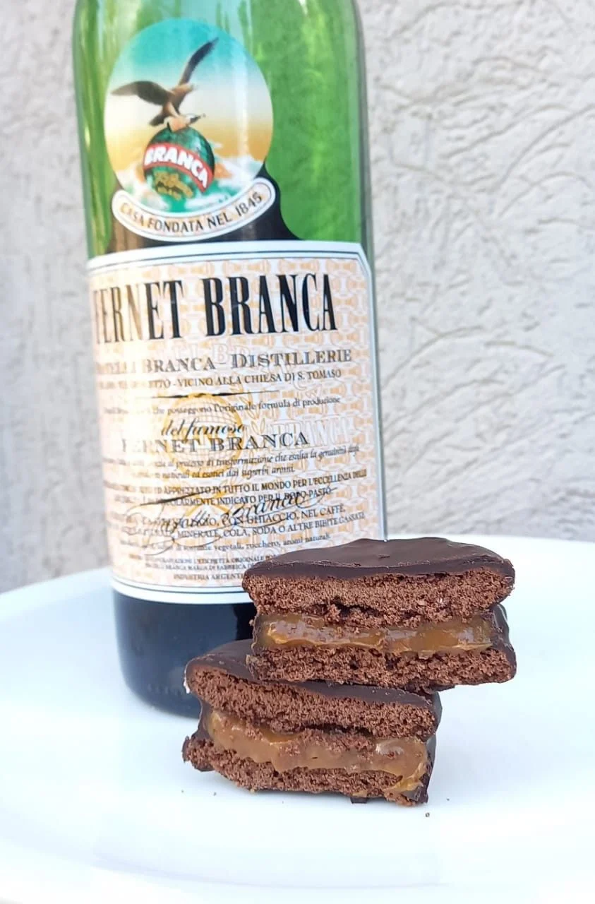 Alfajores de fernet con dulce de leche junto a una botella de fernet