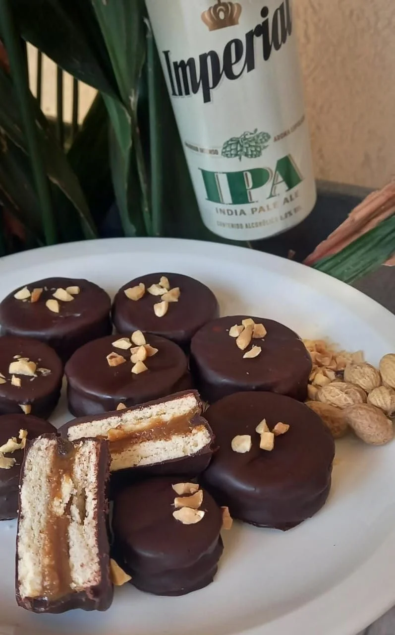 Alfajores bañados en chocolate con maní junto a una cerveza IPA